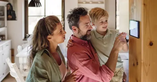 Small family adjusting their home's temperature using a smart thermostat