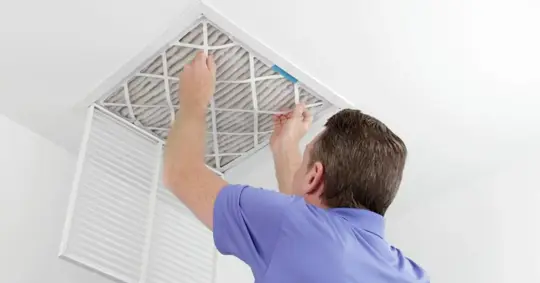 Man removing air filter from vent